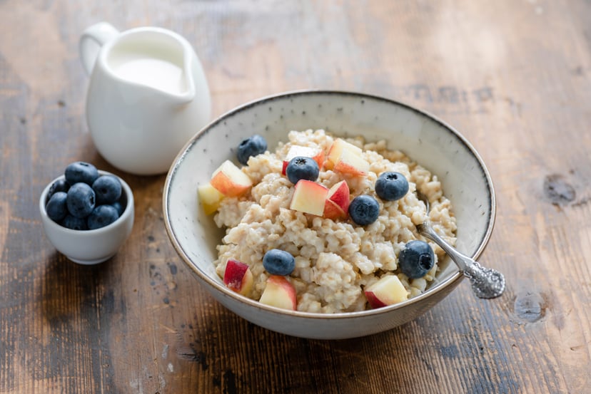 Oatmeal porridge with blueberries and peach. Porridge bowl. Healthy breakfast food. Rustic style