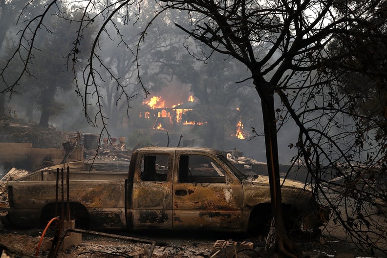 Homes destroyed by the fire can be seen in the background.