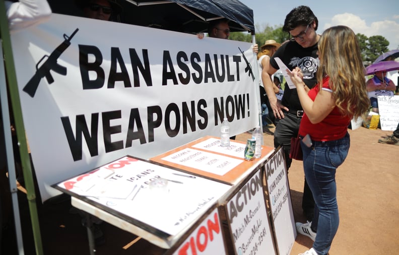 EL PASO, TEXAS - AUGUST 07: A 'Ban Assault Weapons Now' sign is displayed near a voter registration table at a protest against President Trump's visit, following a mass shooting which left at least 22 people dead, on August 7, 2019 in El Paso, Texas. Prot