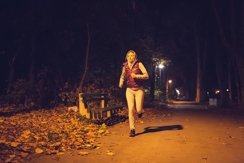 Sporty young woman, night jogging in the park under the street lights