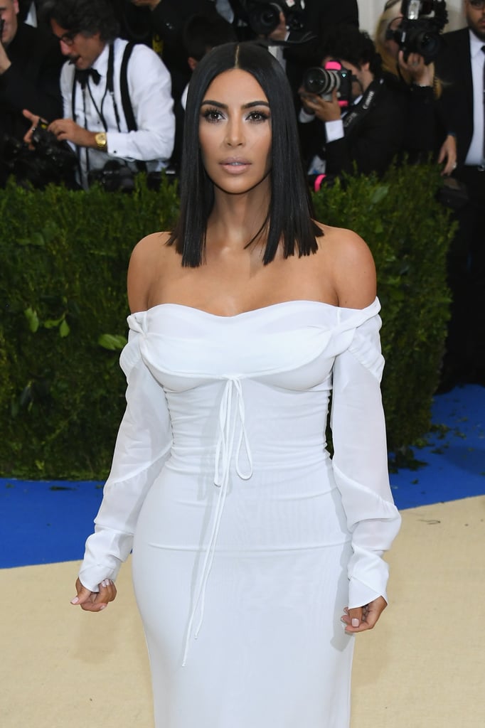 Kim Kardashian arrived by herself at the Met Gala on Monday night in a look that was pretty understated compared to her past ensembles. She walked the red carpet in a white dress and posed for photos solo before likely meeting up with her younger sisters, Kendall and Kylie Jenner. Kim's husband, Kanye West, decided to stay at home in LA with their two kids; People reported earlier in the day that the rapper wasn't quite ready for "the stress and pressure of a big red carpet" since his hospitalization in November and that he is "still very much enjoying his time off from public events." Kim's night at the Met Gala comes on the heels of a very hot girls' getaway to Mexico in celebration of her sister Kourtney's 38th birthday. The two sported barely-there bikinis and lounged on the beach with friends. Keep reading for all the photos from Kim's solo night out in NYC.