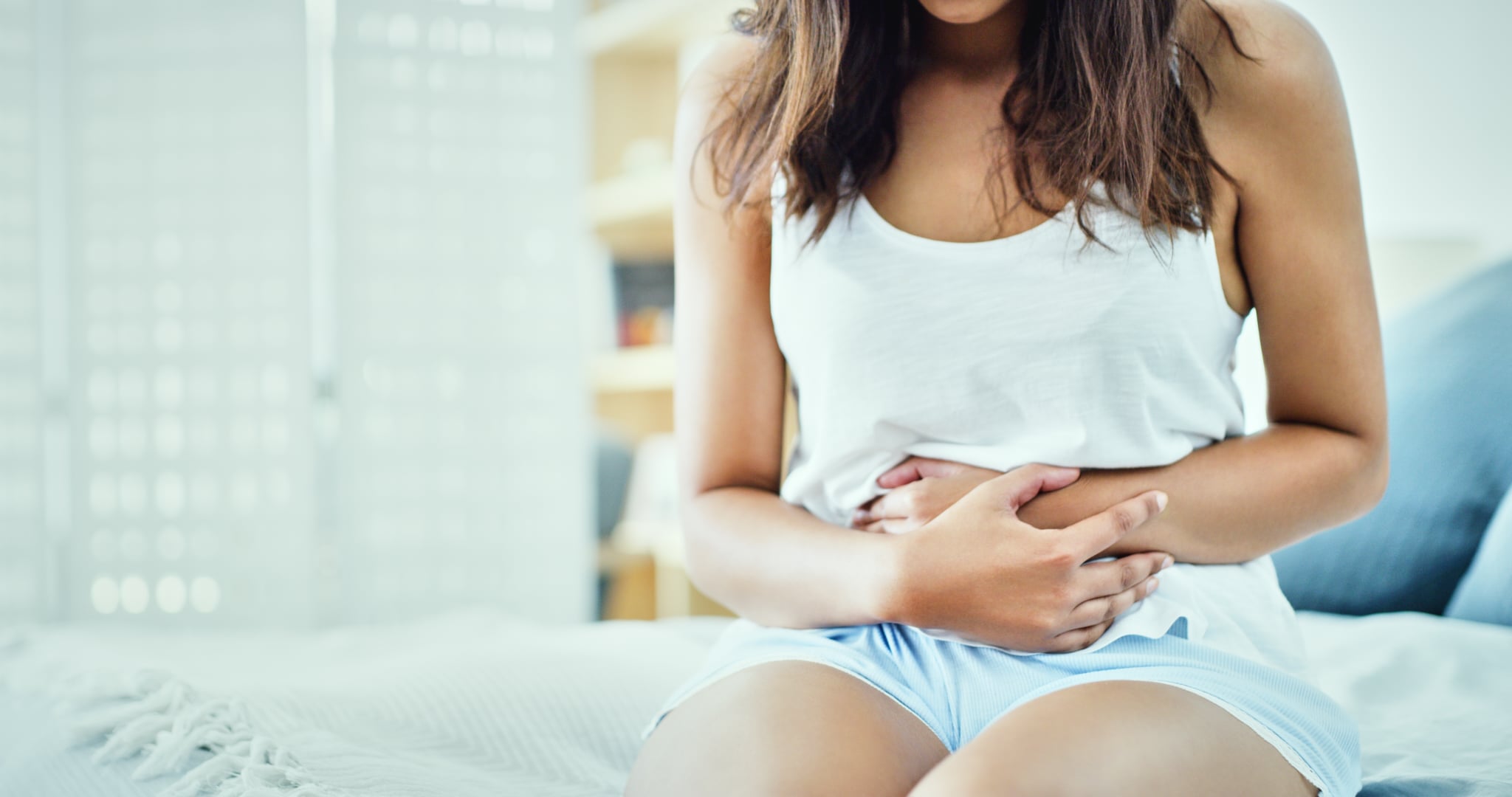 Shot of an unrecognisable woman suffering from stomach cramps in her bedroom