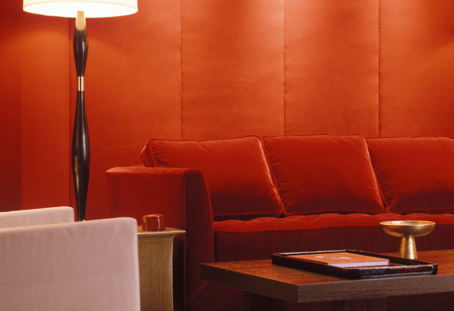 a red velvet couch backdropped by a red wall