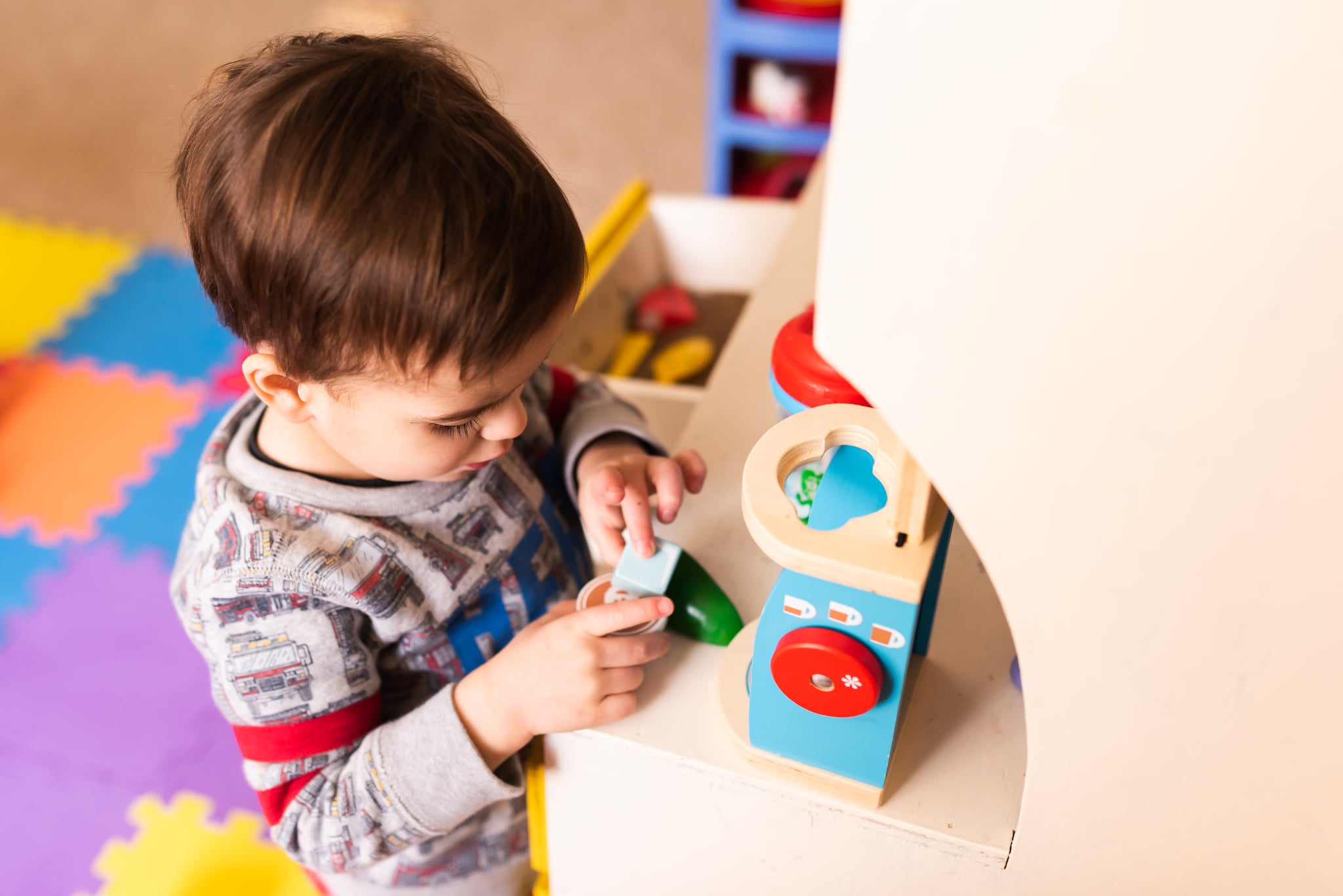 Shot above toddler playing with vintage toys in a kitchenette during a sick day in the basement.