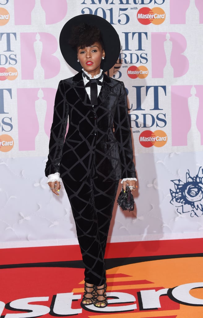 At the Brit Awards, Janelle dressed up a patterned velvet suit with a ruffled shirt, black necktie, and strappy lace sandals, not to mention a wide-brimmed black hat.