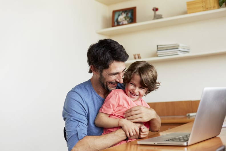 Happy father tickling son at laptop table in house
