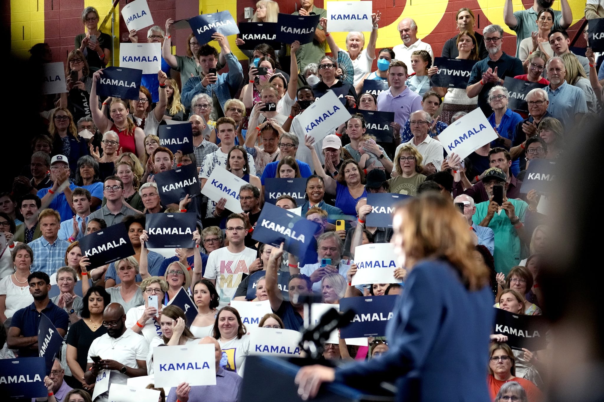 Attendees hold signs as US Vice President Kamala Harris speaks during a campaign event in Milwaukee, Wisconsin, US, on Tuesday, July 23, 2024.