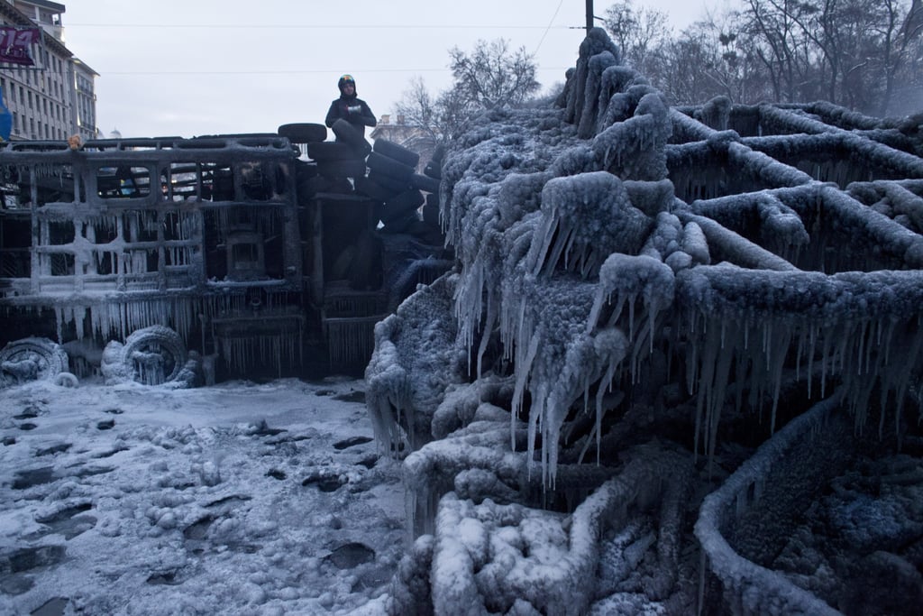 A protester stood on top of a charred, icy police truck.