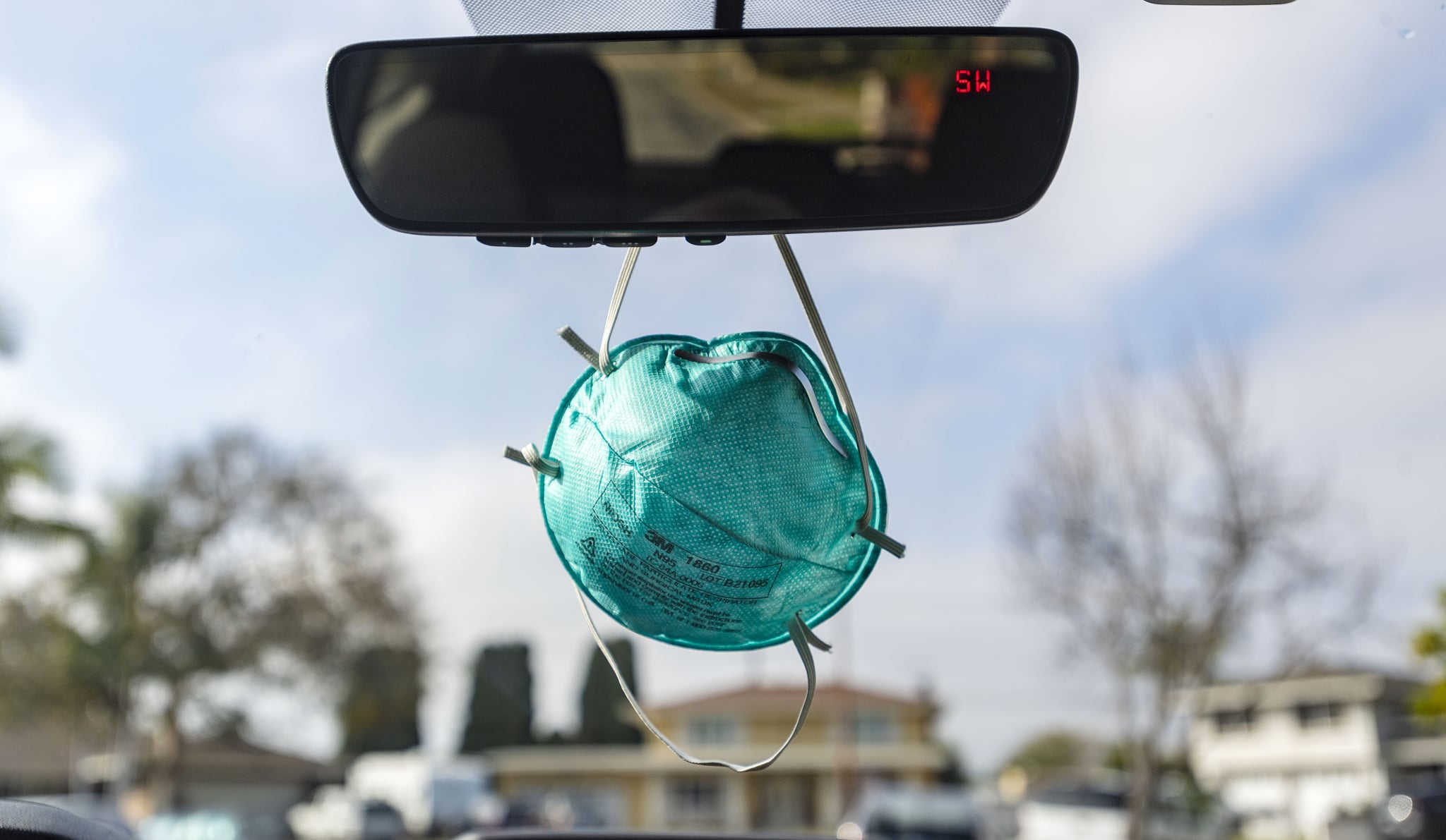 Mask hanging from rearview mirror in car.