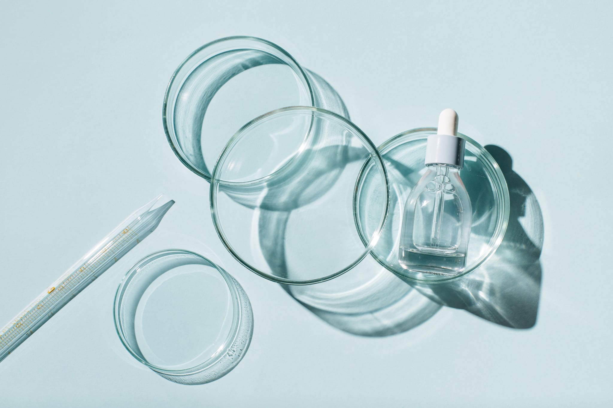 Laboratory glassware and cosmetic glass bottle on blue background. Natural medicine, cosmetic research, bio science, organic skin care products. Top view, flat lay. Research and development concept.