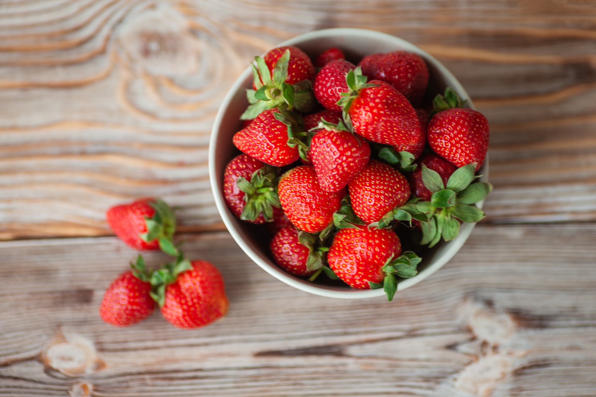 View from the top of a bowl of ripe strawberries, standing on a wooden table.Close-up.