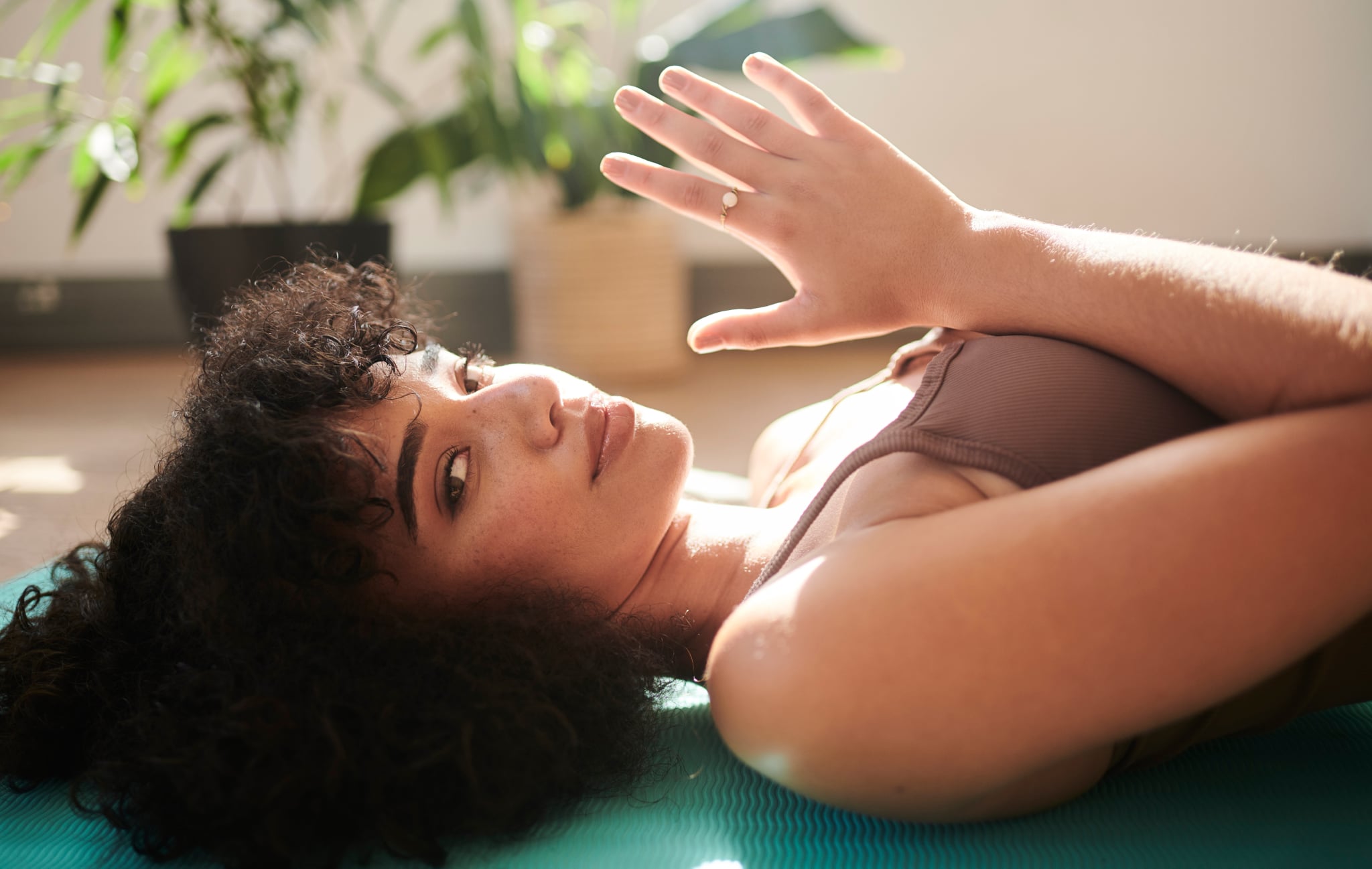 Woman Laying Flat on Her Back In Yoga Studio Holding Hands in a Prayer Pose