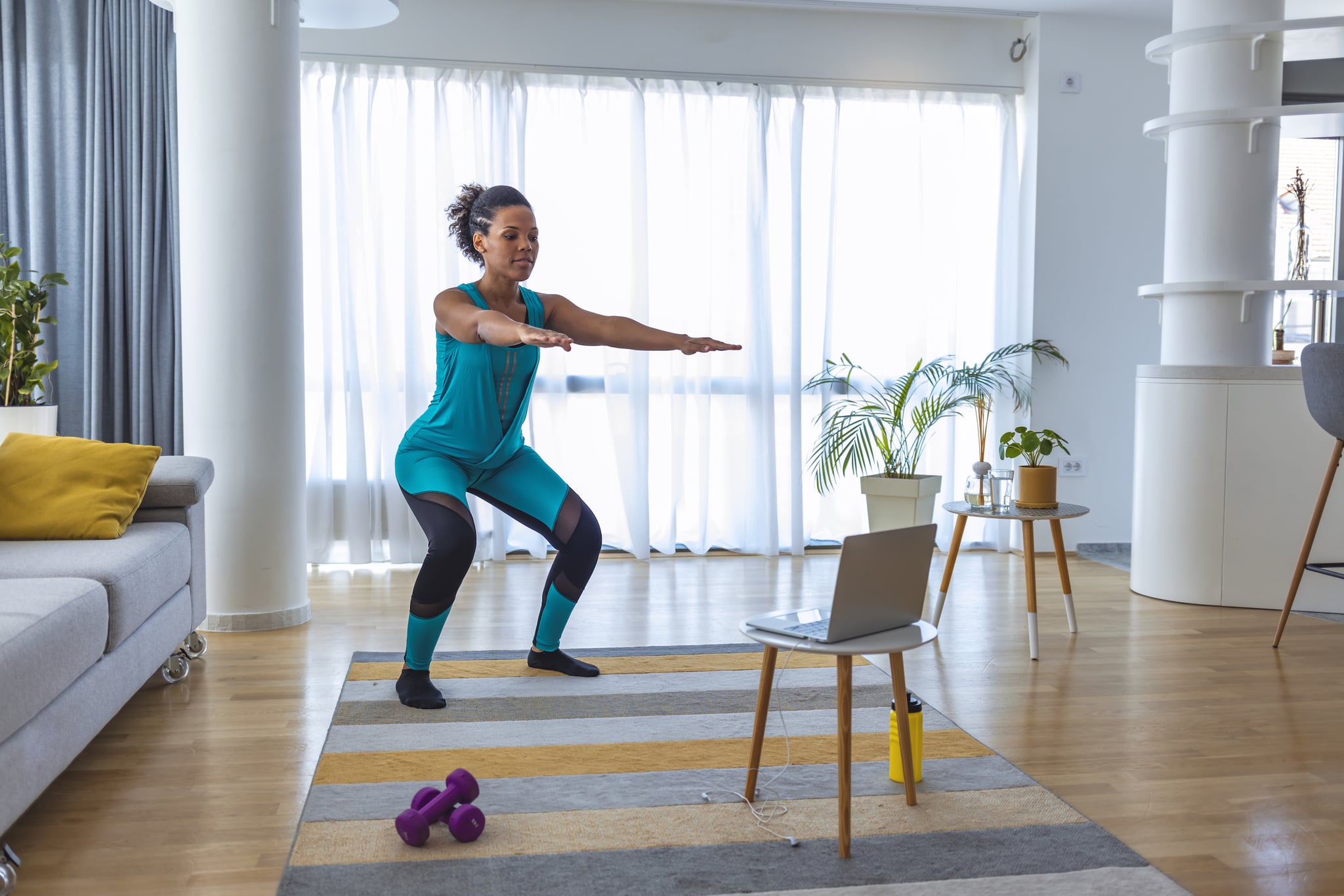 Beautiful  African-American Woman Exercising Pilates, Yoga, Fitness at Home Looking at the Laptop.