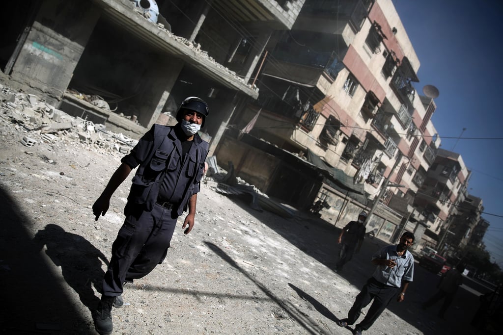 A White Helmet walks through damaged buildings following an airstrike in Douma.