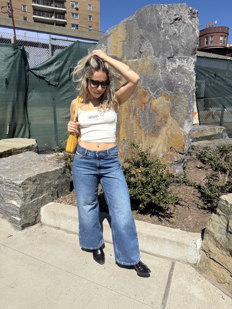I'm almost always going to channel the '90s (with a subtle Western touch) when it comes to festival season. I instantly gravitated towards Guess's basics: a midriff-baring tank is perfect for when the sun's beating down, as long as I remember to lather up in SPF; and these lightweight, low-rise jeans somehow toe the line between structured and movable in the best way, without being so soft that they feel like leggings. This Guess marigold shoulder bag is iconic — I just had to match it to the Fendi logo on my sunglasses. 
Outfit: GUESS JEANS Embroidered Logo Slim Tank ($29). GUESS JEANS G11 Wide-Leg Jeans ($89). Guess Janie Logo Shoulder Bag ($108).
