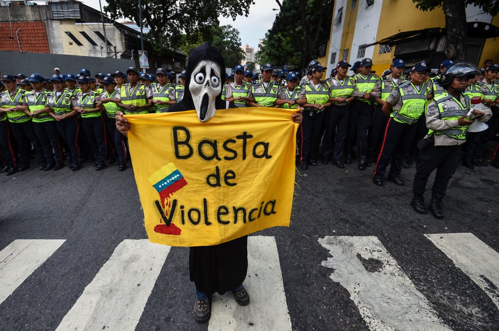 Someone holds a sign that reads "Enough of the Violence."