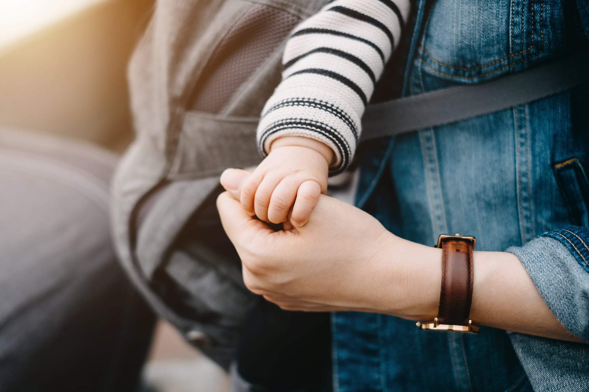 Close up of mother carrying baby and holding hand