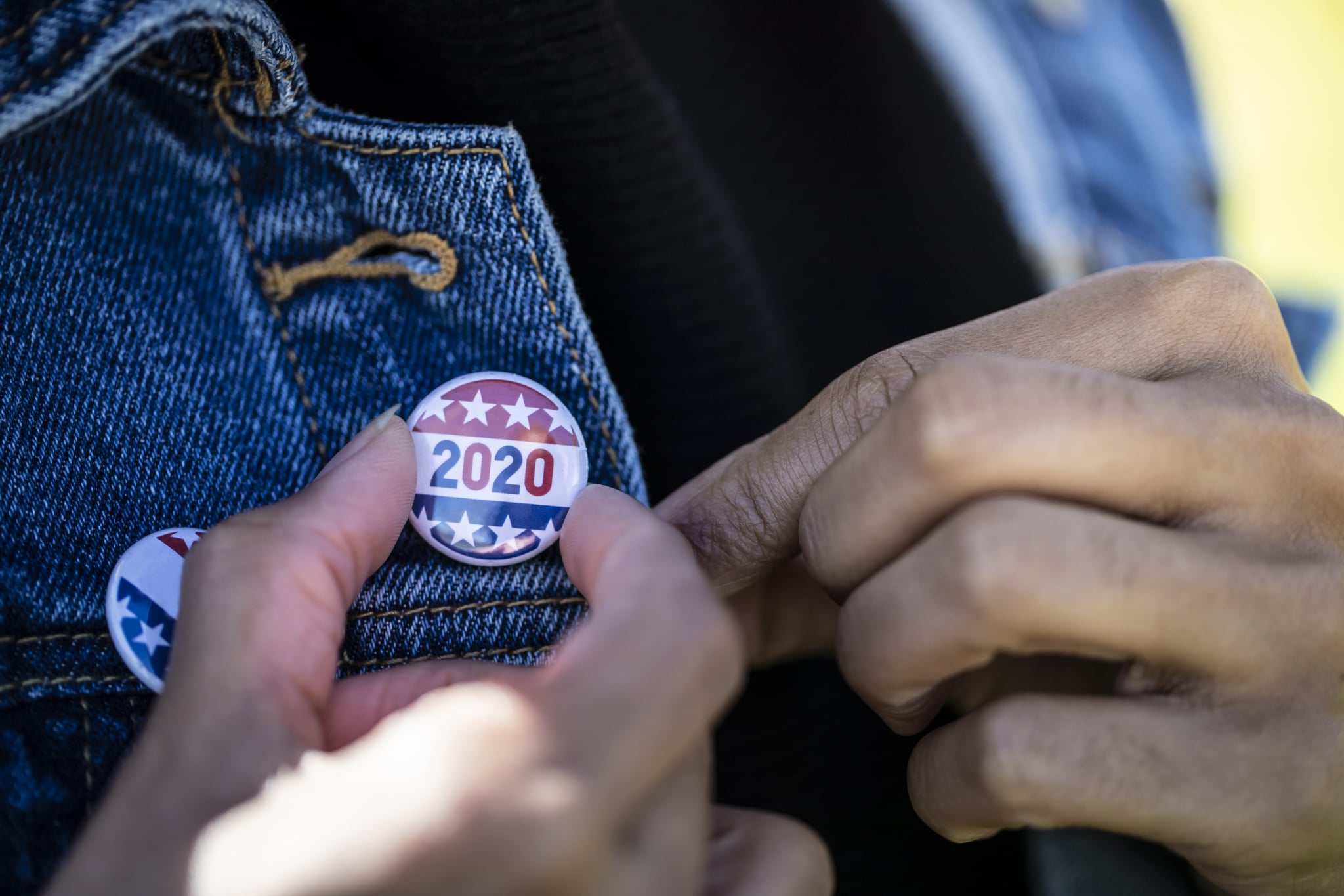 A young African American woman holding a voting badge.