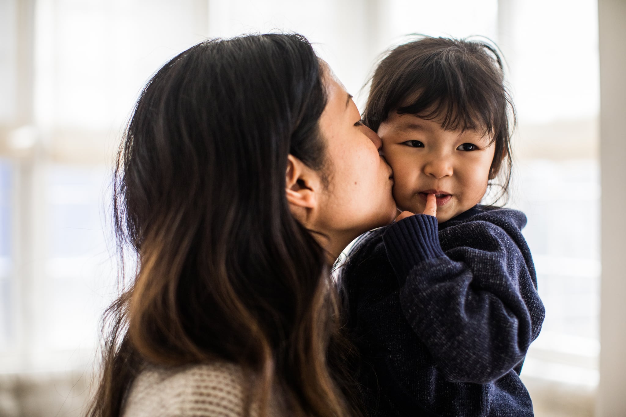 Mother kissing daughter (2yrs) on cheek