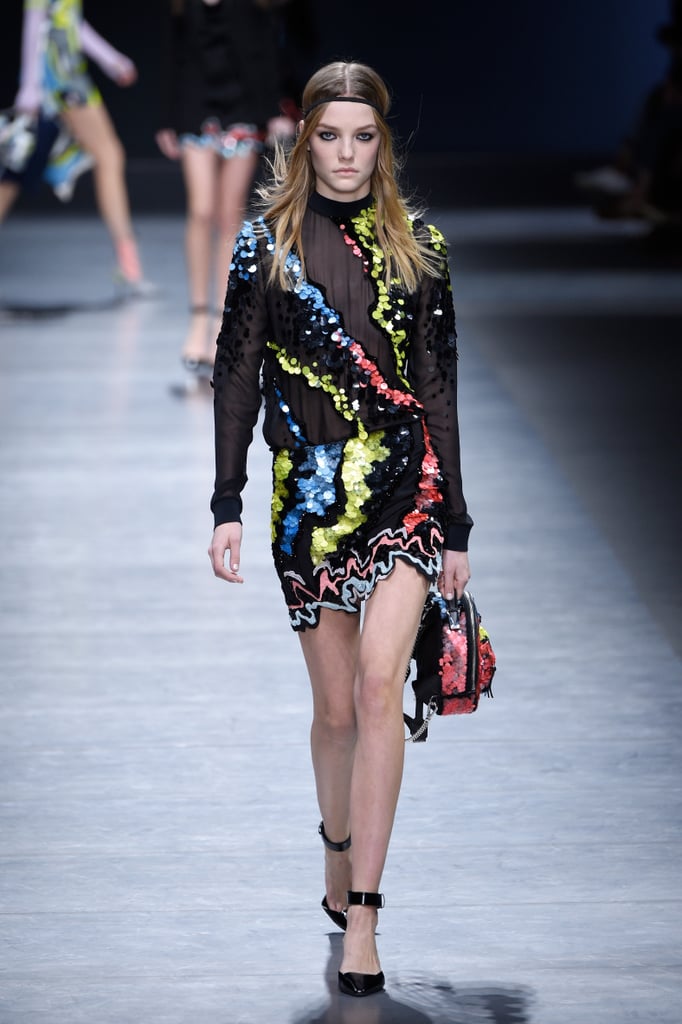 The sheer mockneck and sequined miniskirt debuted on the runway with patent leather ankle-strap heels and a matching backpack.