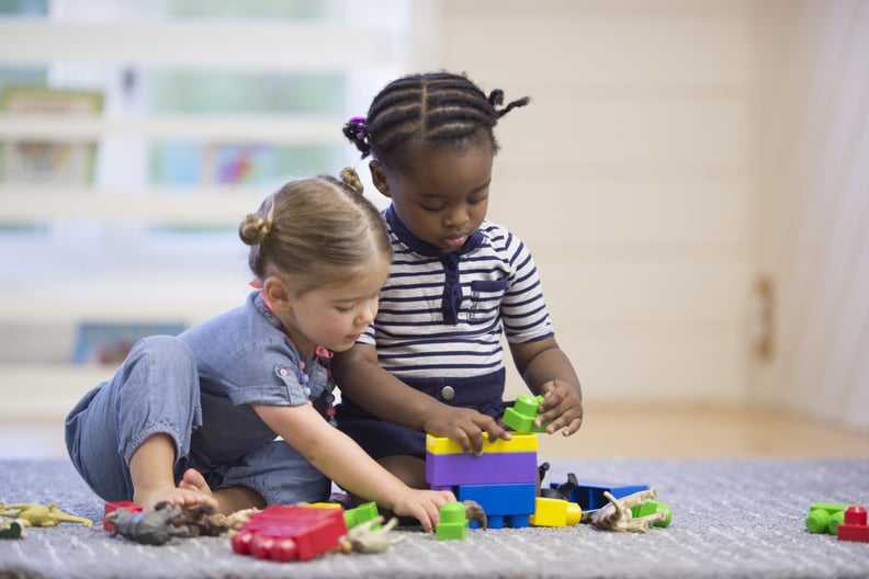 A multi-ethnic group of preschoolers are playing with plastic blocks together in class.