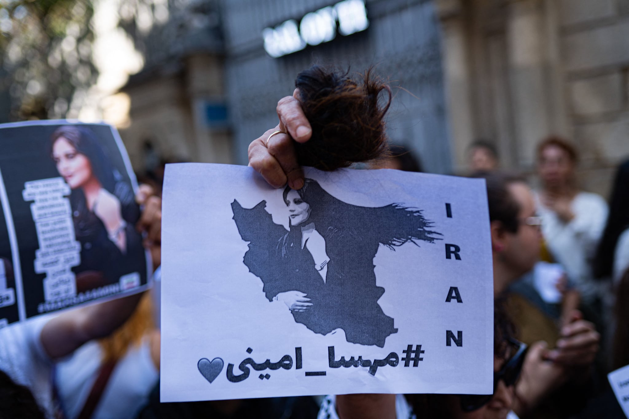 Una mujer iraní que vive en Turquía sostiene una bola de su cabello cortado y un cartel de Mahsa Amini, durante una protesta frente al consulado iraní en Estambul el 21 de septiembre de 2022, luego de la muerte de un Amini iraní luego de su arresto por la moralidad del país. policía en Teherán.  - Mahsa Amini, de 22 años, estaba de visita con su familia en la capital iraní, Teherán, cuando fue detenida el 13 de septiembre de 2022 por la unidad policial responsable de hacer cumplir el estricto código de vestimenta de Irán para las mujeres, incluido el uso del velo en la cabeza. público.  Fue declarada muerta el 16 de septiembre de 2022 por la televisión estatal tras haber pasado tres días en coma.  (Foto de Yasin AKGUL/AFP) (Foto de YASIN AKGUL/AFP vía )