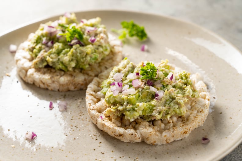 Rice cake with avocado and tuna salad with red onion.