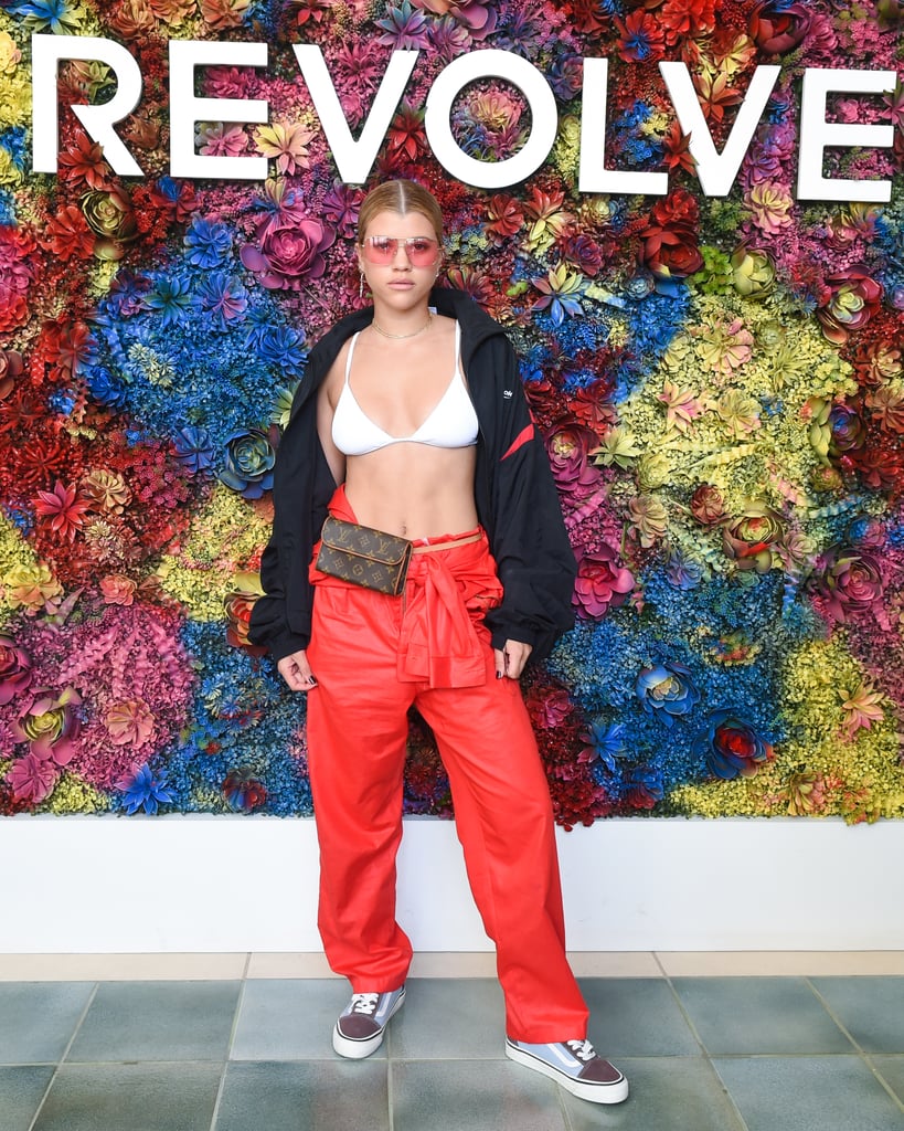 Sofia Richie wearing red trousers, a bikini top, Vans sneakers, and a Louis Vuitton waist bag at the Revolve festival.
Sofia Richie wearing red trousers, a bikini top, Vans sneakers, and a Louis Vuitton waist bag at the Revolve festival.