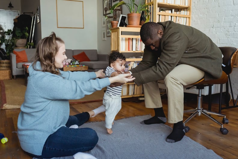 parents holding up their baby starting to walk