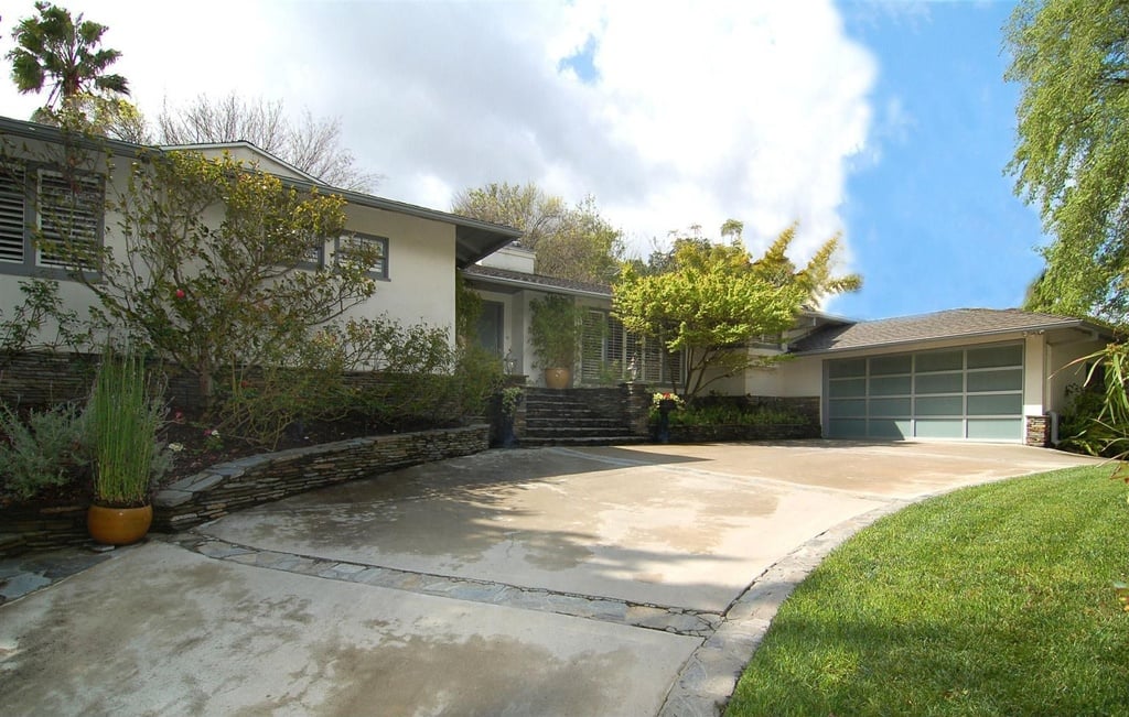 The front of the home has a sprawling driveway leading to the garage. 
Source: Sotheby's Realty