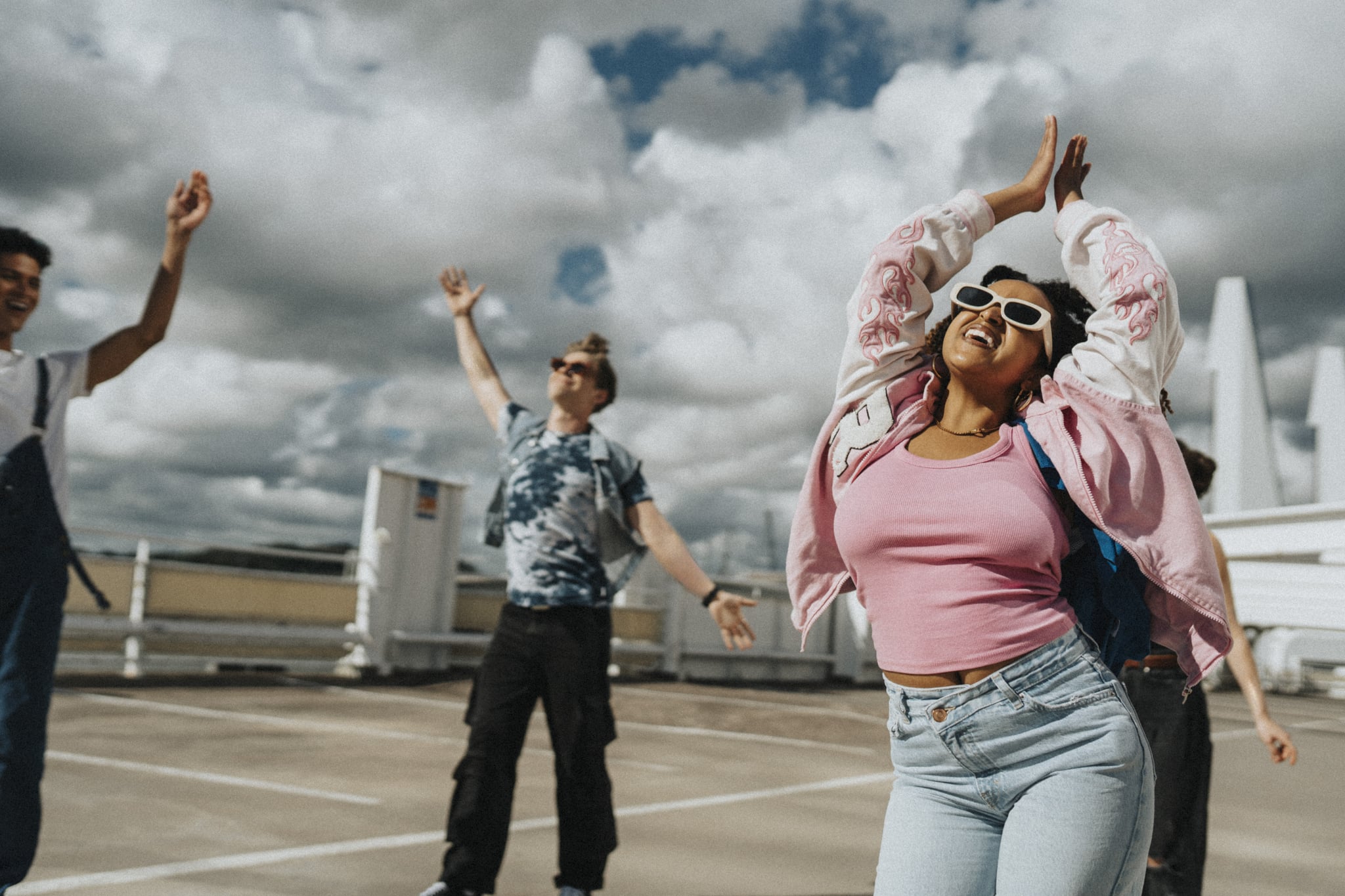 Woman dancing with friends in parking lot.