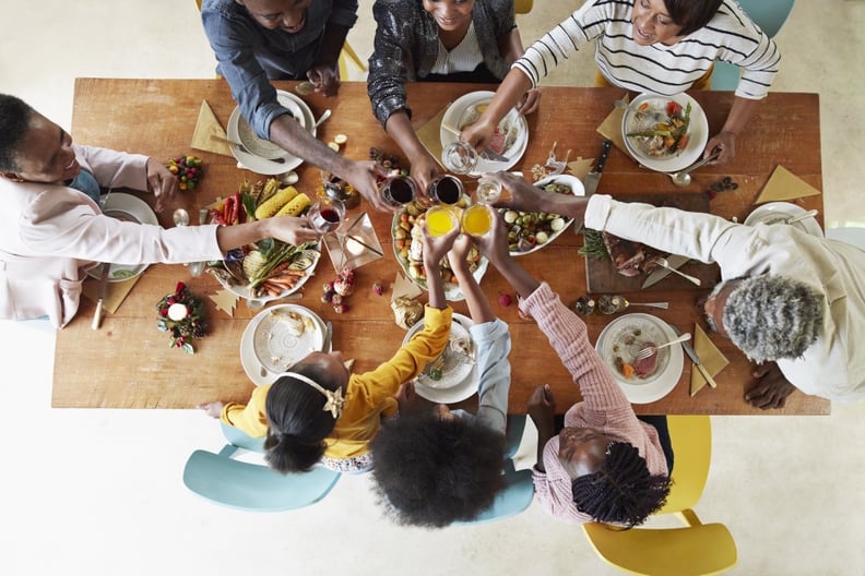 Directly above shot of family and friends toasting drinks while enjoying meal at home during Christmas