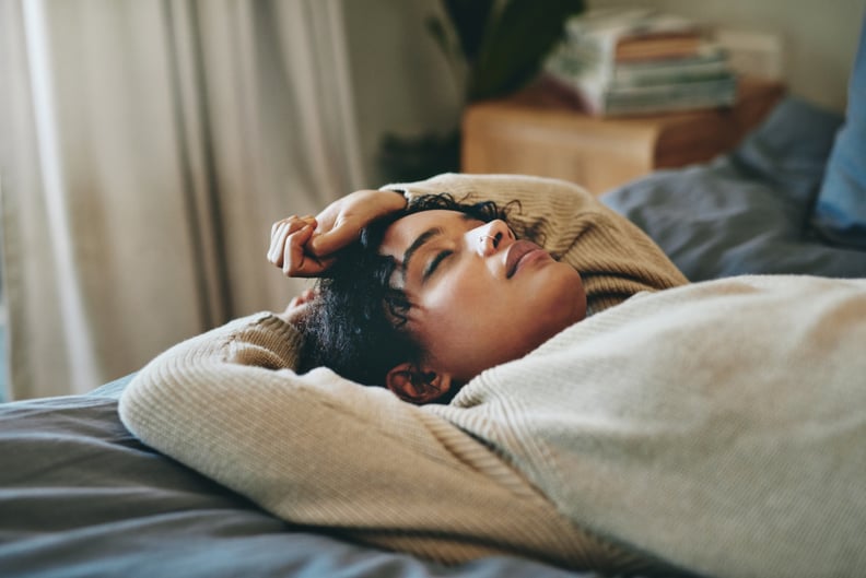 Young woman lying on her bed with her eyes closed