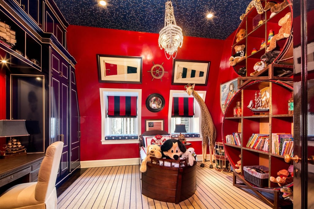 This red and navy children's room spares no expense, from the lacquered built-ins to the crystal tall ship chandelier.