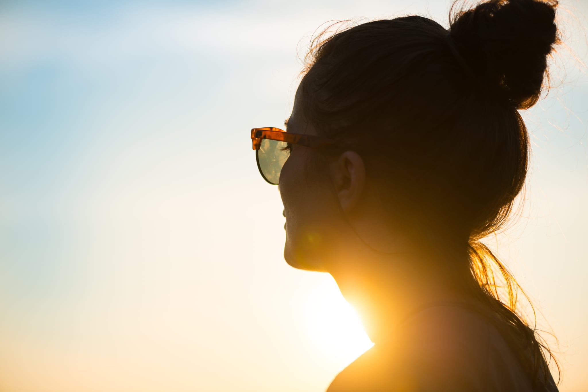 Young woman wearing sunglasses looking at sunset