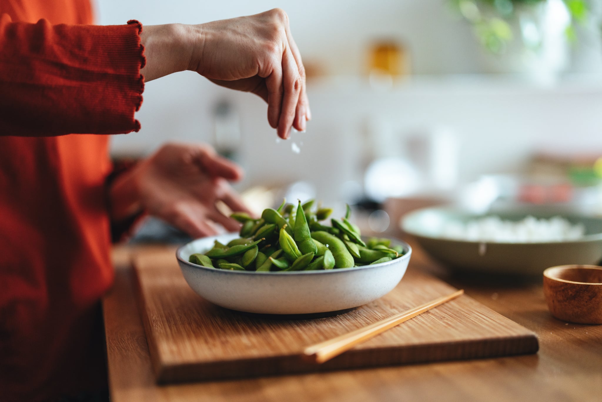 Woman preparing edamame as a veggie snack. Woman preparing edamame as a veggie snack.