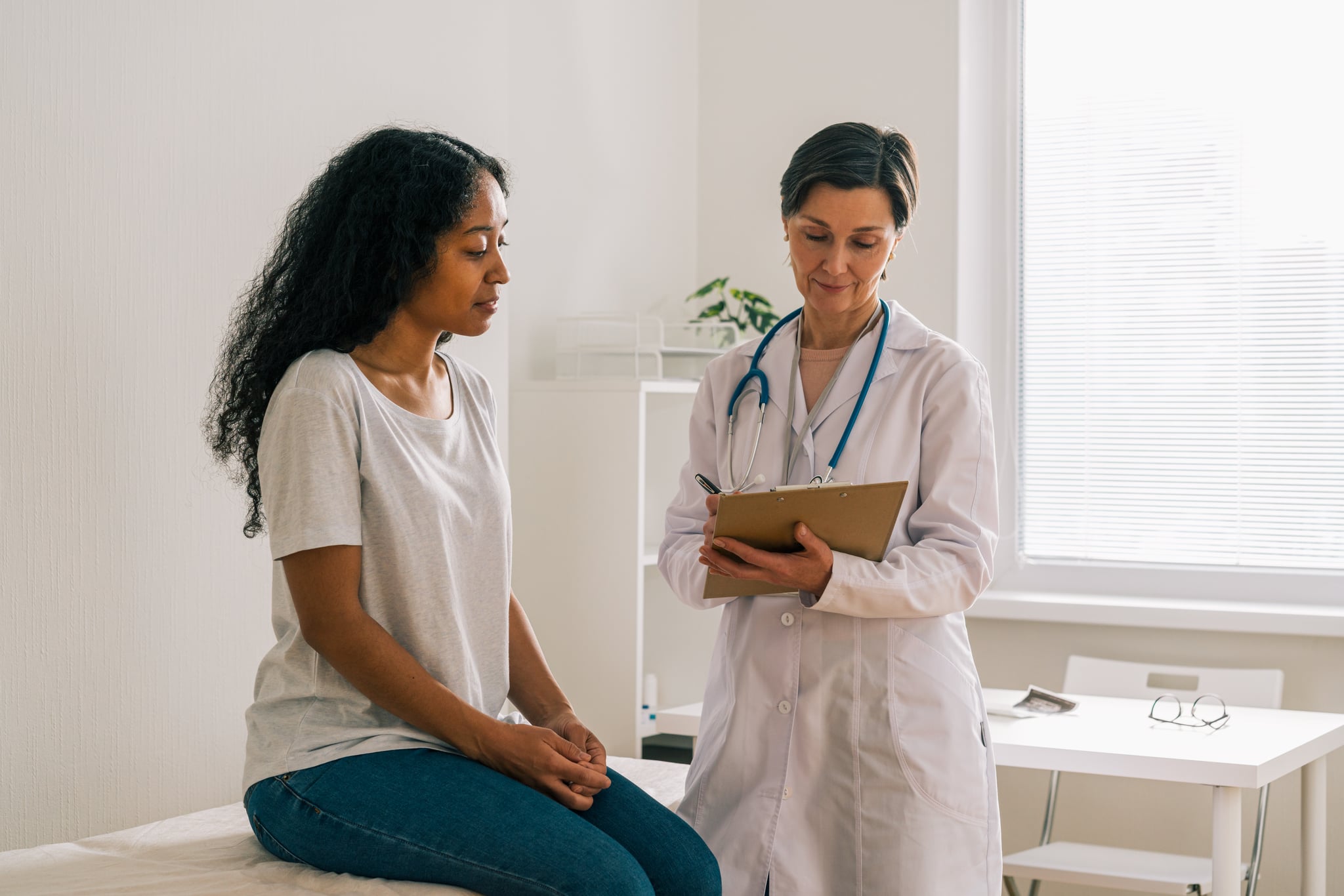 African-American female listening carefully to advice and recommendations of doctor. Healthcare consultation and examination in medical clinic office. Prescribing medications and treatment