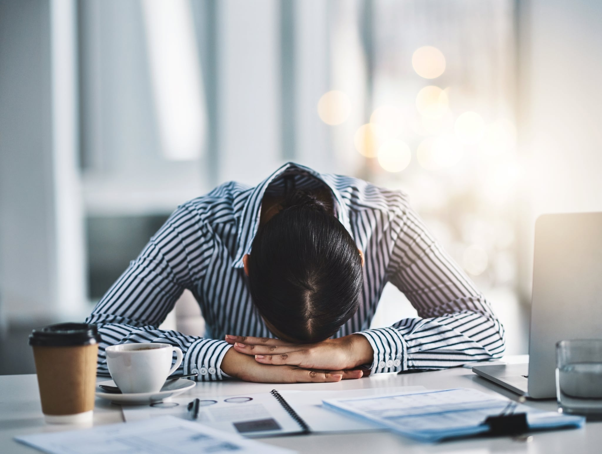 Shot of a young businesswoman lying with her head down on a desk in an office