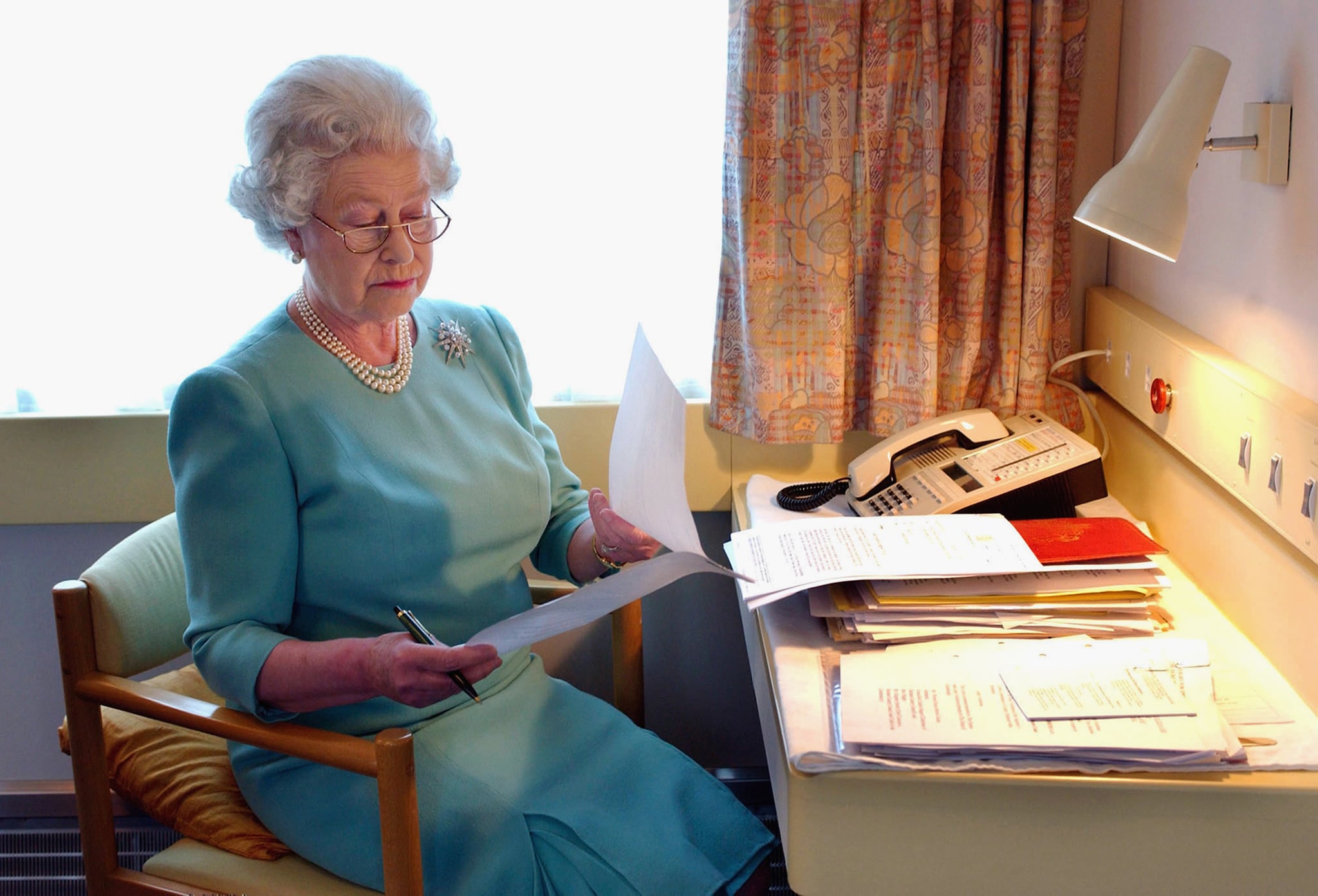 Queen Elizabeth II reviews papers on her train in 2002