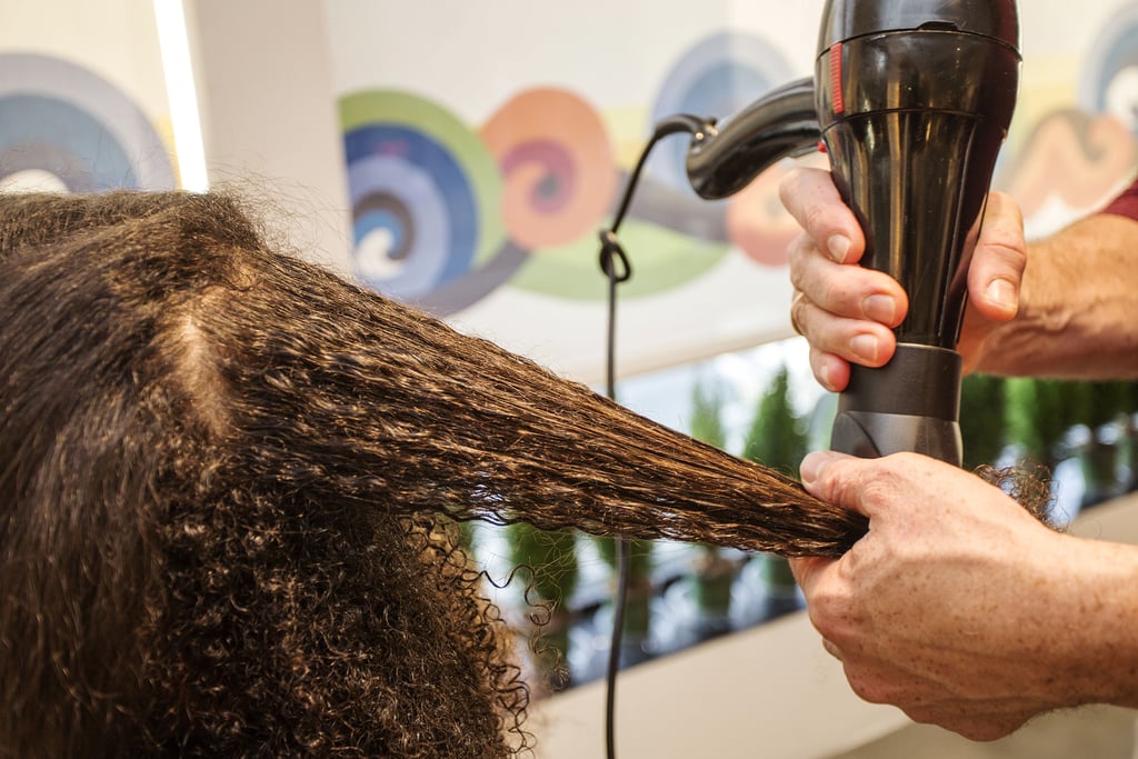 After prepping hair with Hair Rules Blow It All Out ($16) to fight humidity, Dickey sectioned off the hair and began to blow-dry. 
To ensure that there will be minimal tangling and maximum protection, Dickey suggested using a comb attachment. "[This way,] there is no extra tension on the hair — you're basically just detangling," he explained. "And it's always moving, so it's not burning your hair."