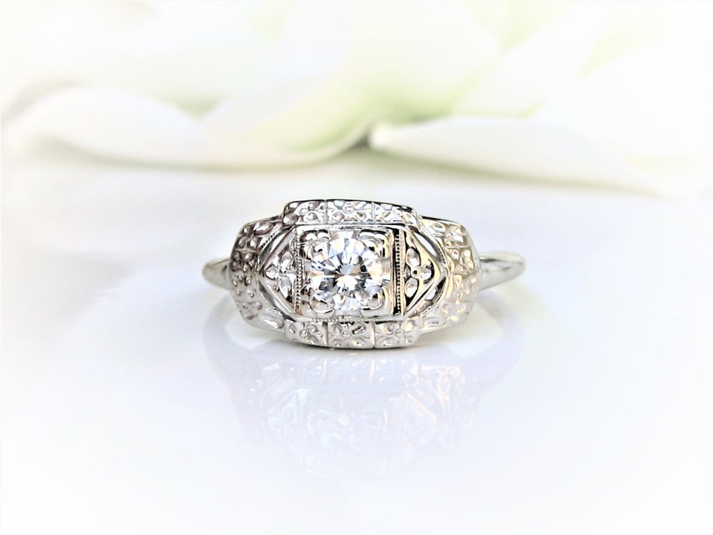 This elegant and detailed art deco engagement ring ($645) features a center diamond and 14k white gold setting with tiny decorative gold orange blossom detailing.