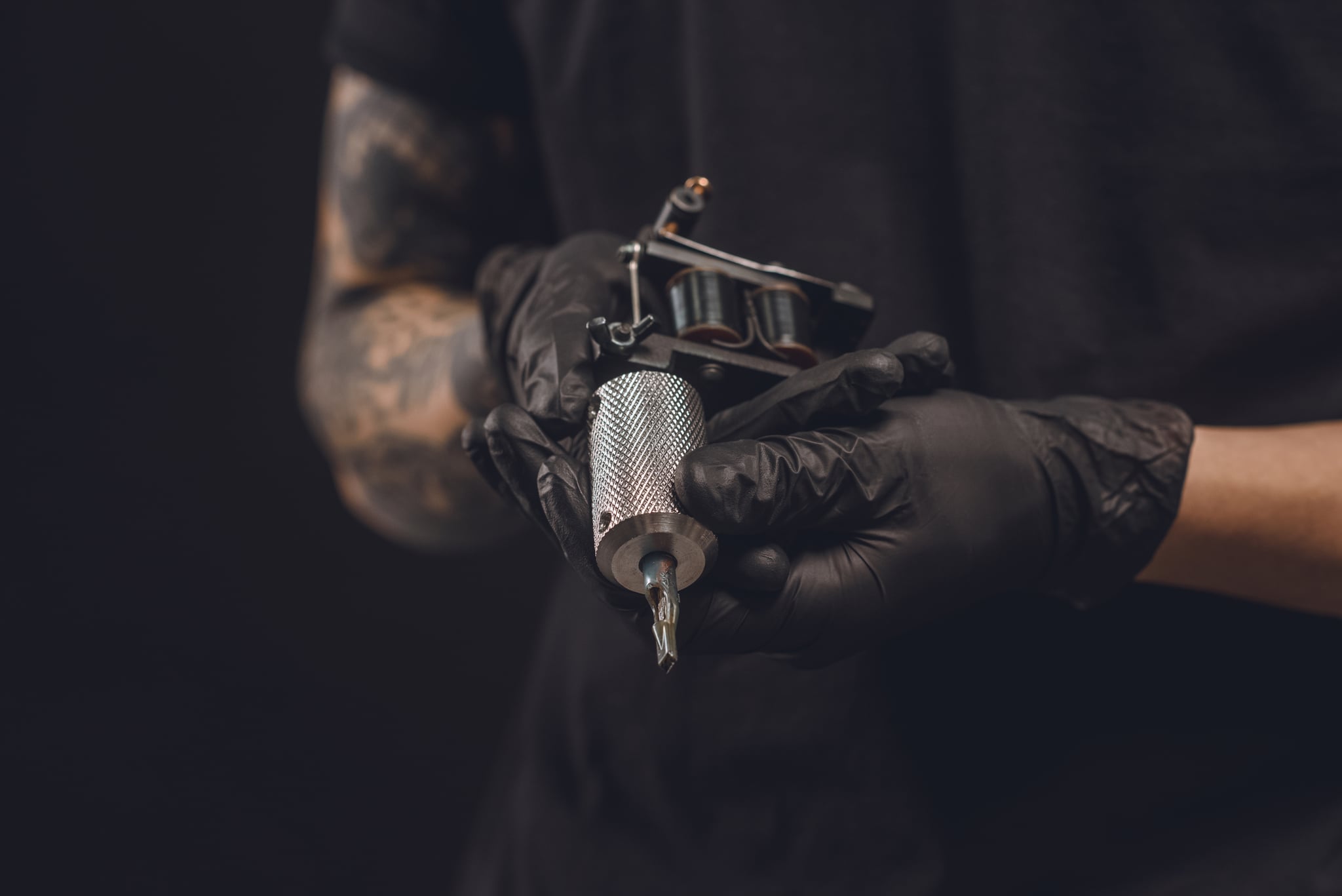 男性的手在手套纹身机孤立在黑色