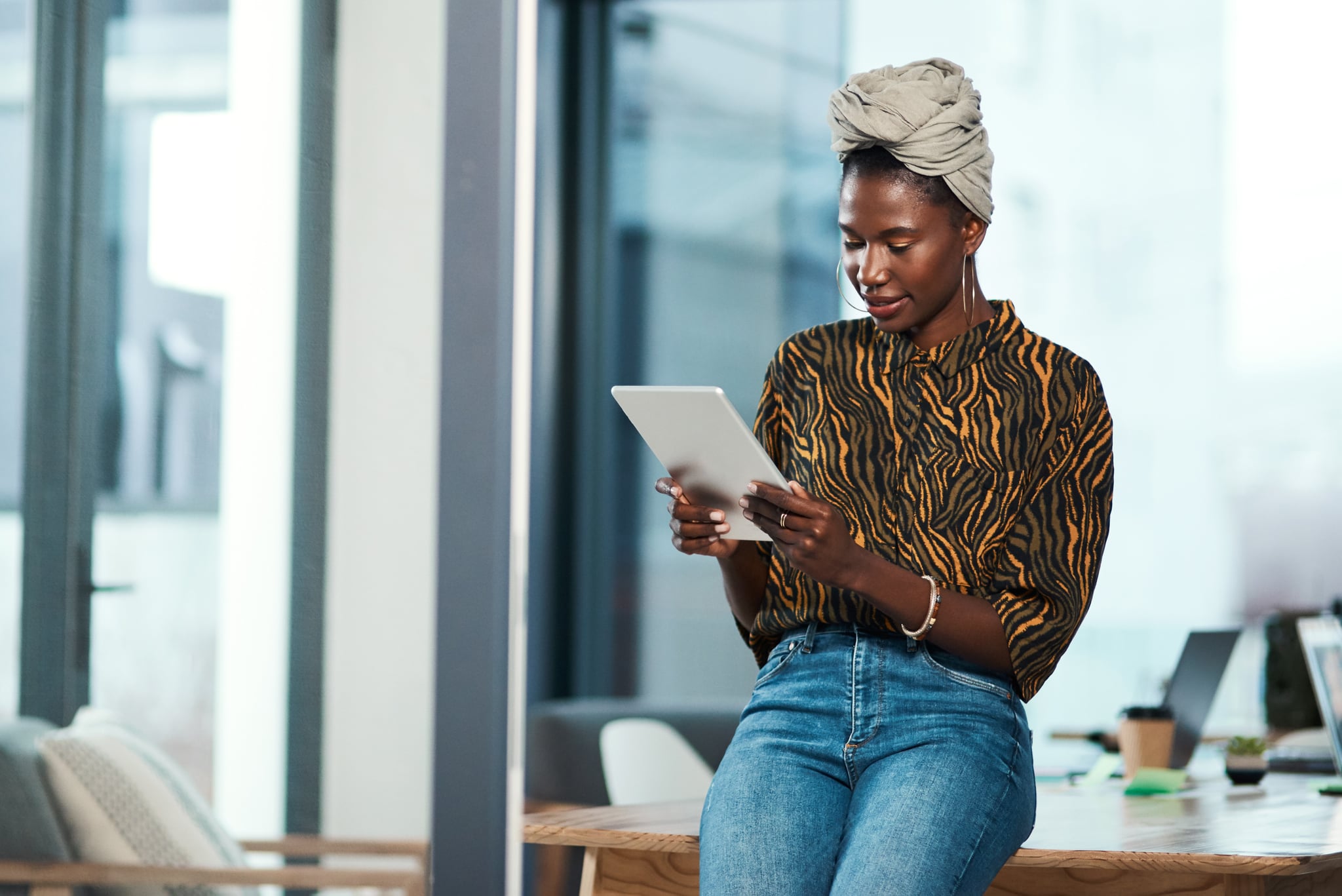 Cropped shot of an attractive young businesswoman sitting alone in her office and using a tablet