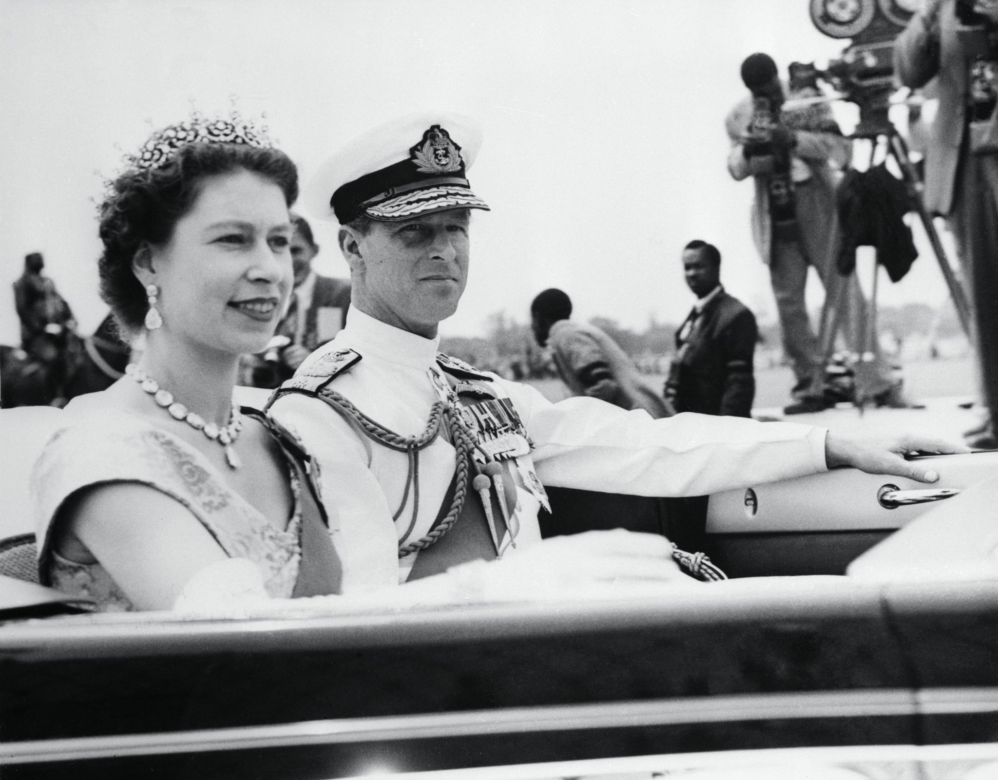 (Original Caption) Britains Queen Elizabeth wearing a tiara, is accompanied by the Duke of Edinburgh, as she leaves the pavilion where she watched a cavalry charge by colourful native horsemen. The royal couple is on a ceremonial tour of the African colony.