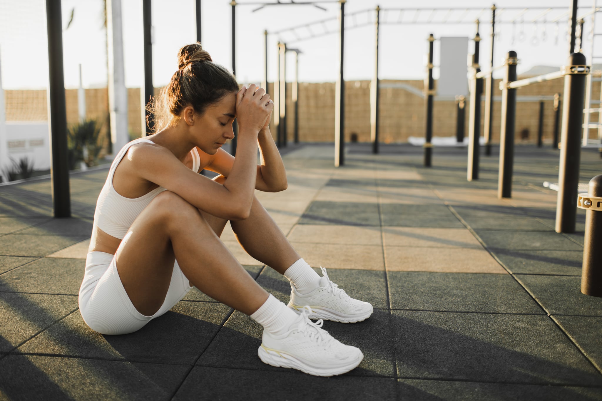 Woman sitting on the gym floor, dealing with exercise addiction.