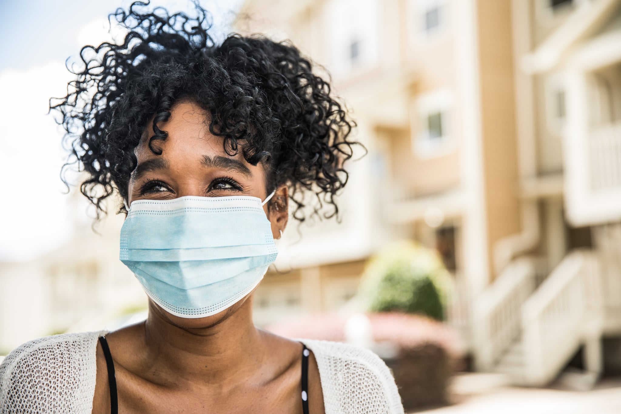 Young woman wearing surgical mask in front of home