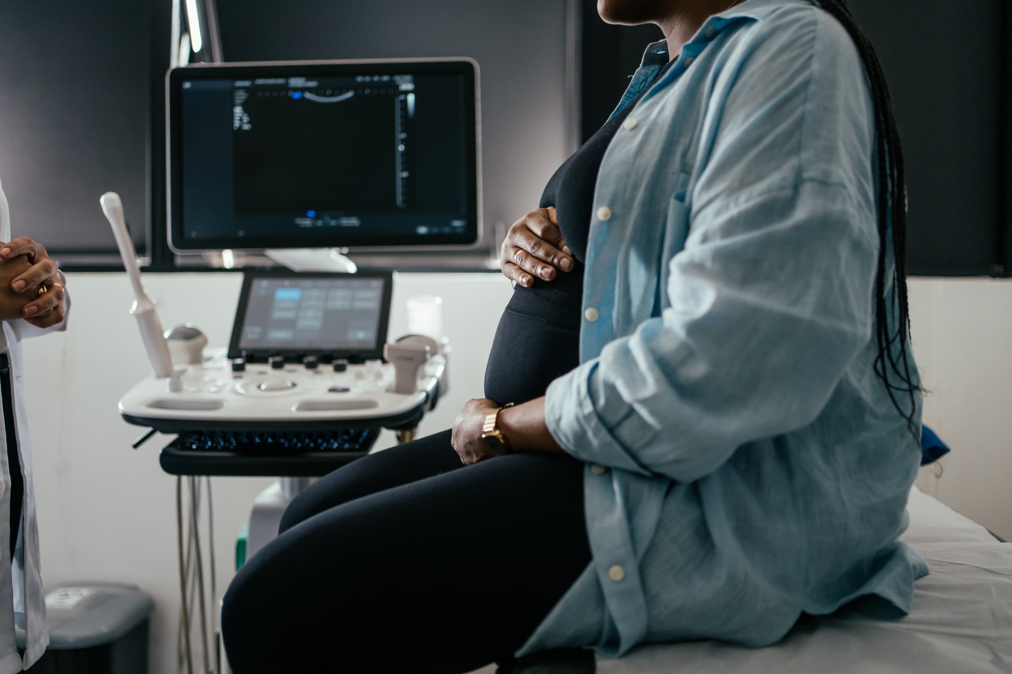 Pregnant woman holding her belly during a prenatal exam.