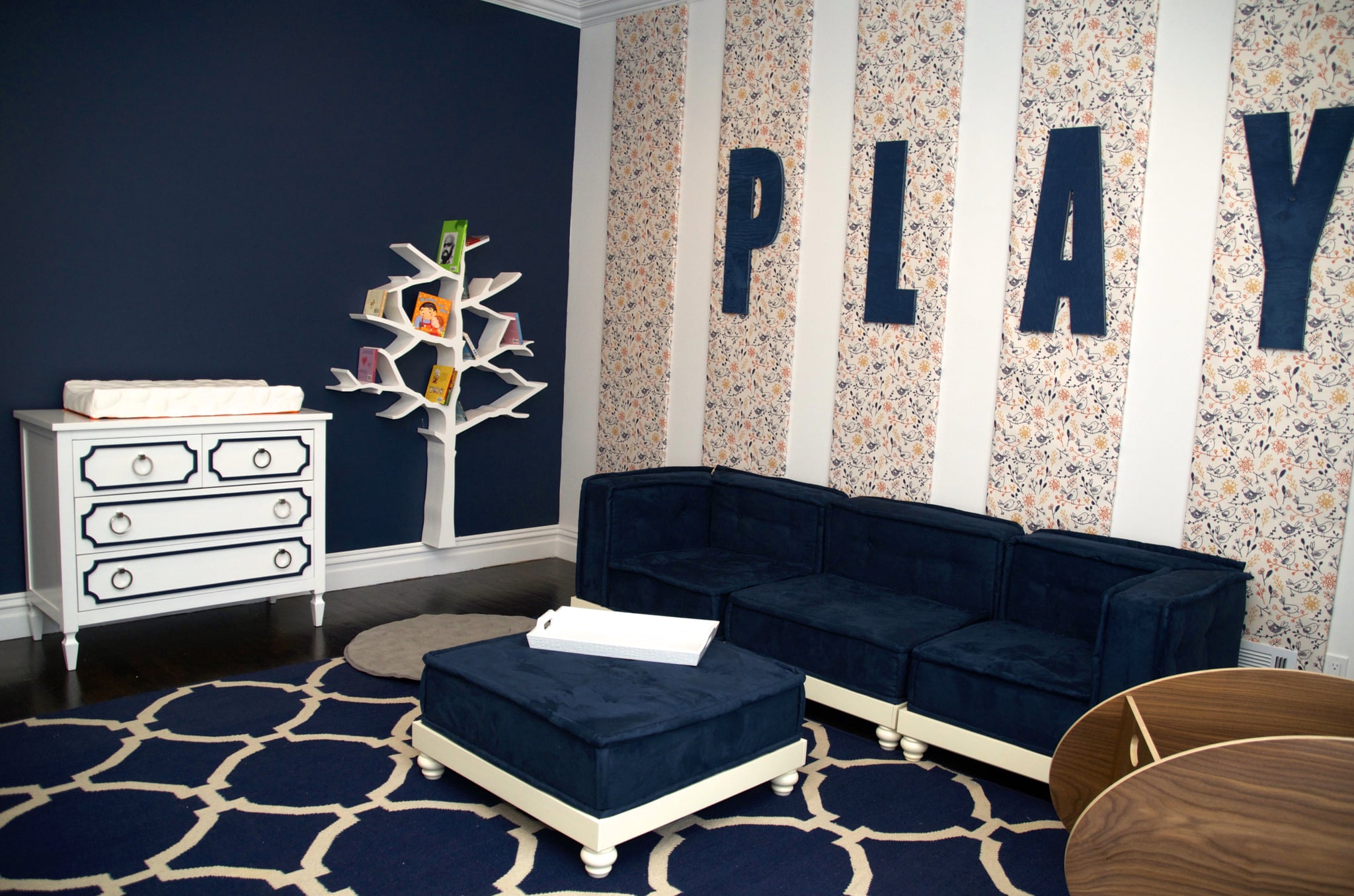 PS: Vanessa, tell us about some of the individual pieces you incorporated into the room.
VA: Each time I would pick a piece for the room, I'd say to myself, "This is the focal item." Well, obviously everything can't be "the item," so here I have a room with [everything that I thought could be] a focal on its own, because they're all so perfect. 
The Nurseryworks Tree Bookcase isn't only beautiful to look at — it's very functional. It holds more than 100 books. The Newport Cottages Beverly Changer brings a little glam into the room with its Hollywood Regency feel. The couch is from Pottery Barn Teen. It's low to the ground so that as Alena learns to walk and climb, it'll be safe and easy. Since Alena is too little to really play right now, I put a BabyHome So Ro Bassinet in the room so that Kevin and Danielle could immediately start spending time in there.
The bird wallpaper took me forever to find, but when I finally did, I knew it was the one! It's by a company in Australia called Muffin & Mani. I expect many of their designs to turn up in my rooms from now on! The giant PLAY letters by Twelve Timbers make it very clear that a lot of fun is going to happen in this room! By mounting them on the wallpaper panels, it gave the room even more dimension. The area rug is by Jaipur, and in addition to being a perfect anchor for the space, it's very light and easy to roll up and take outside to shake out because we all know, messes happen.
Source: Vanessa Antonelli for Nessa Lee Baby