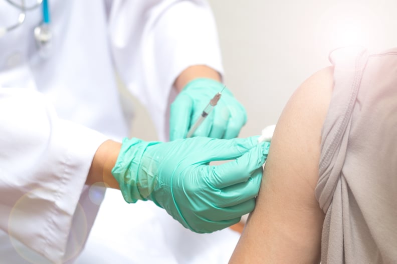 Vaccination healthcare concept. Hands of doctor or nurse in medical gloves injecting a shot of vaccine to a man patient