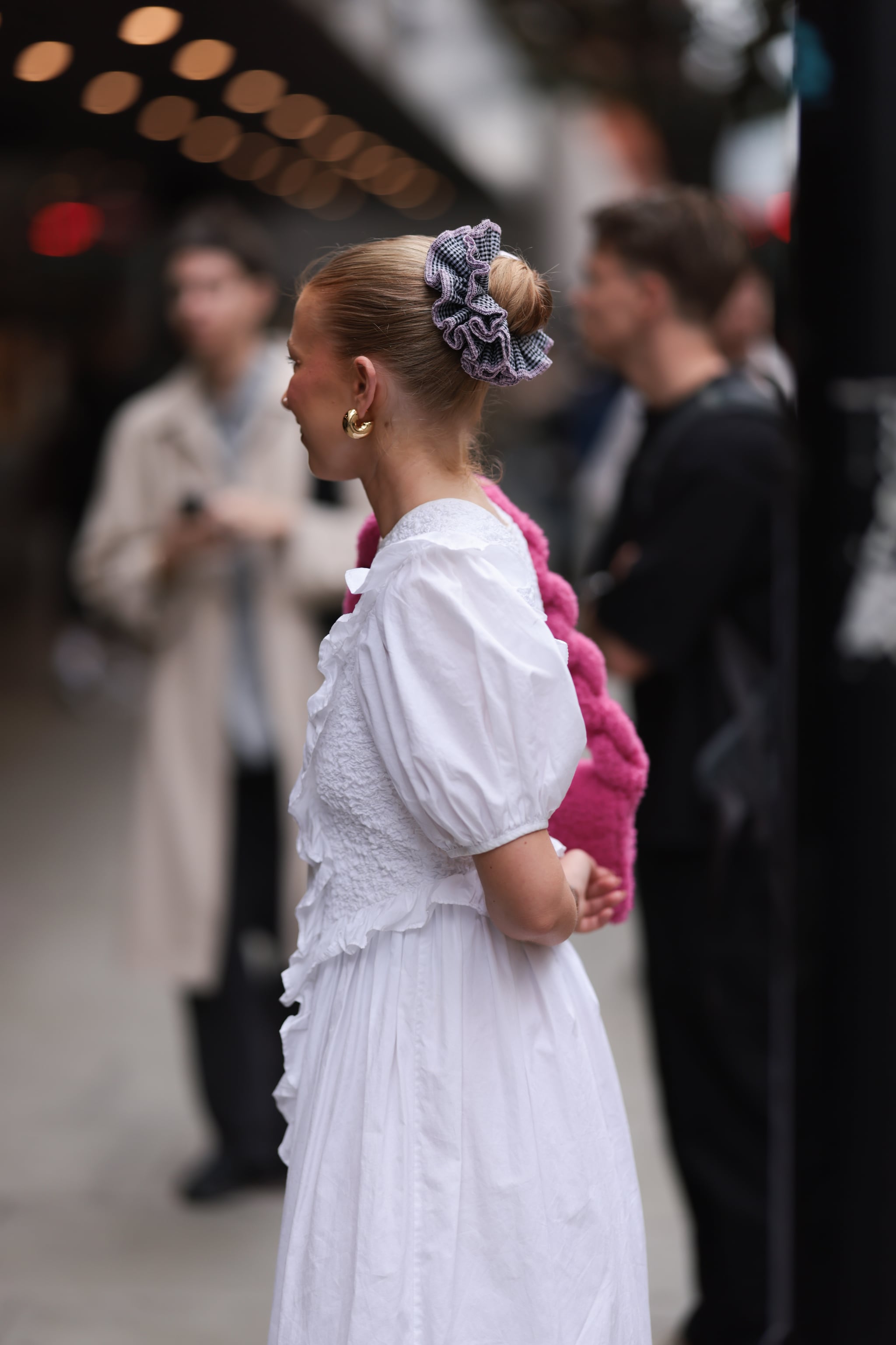 LONDON, ENGLAND - SEPTEMBER 17: Fashion Week Guest was seen wearing black leather shoes, a purple hairband along with yellow gold earrings, a white long dress and a pink bag next to a person wearing dark shoes, a long black skirt, a black bag, black earrings and a black and green colored half open shirt with collar during London Fashion Week September 2023 at the MASHA POPOVA Fashion Show on September 17, 2023 in London, England. (Photo by Jeremy Moeller/Getty Images)